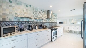 A modern kitchen with white cabinets, a microwave, toaster, and a stove. - SUNSHINE DREAM HOUSE WITH HEATED POOL, NEAR BEACH, CLOSE TO SOUTH BEACH (Dania Beach)