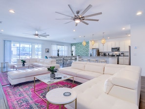 Relax in a spacious living area with a large sofa and coffee table, complemented by a colorful rug. Enjoy a well-equipped kitchen and dining area with a large table.