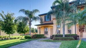 A two-story house with a paved driveway, palm trees, and a well-maintained lawn. - 4BR Regal Palms Townhome by FS FL VH-154 (Davenport)