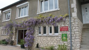 Un bâtiment en pierre avec une enseigne indiquant « Gîte la Boussière » et un panneau vert orné d’un symbole représentant une maison.