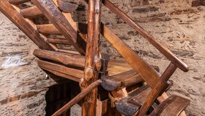 A wooden spiral staircase with a rustic stone wall background. - Self catering El Mirador de Robledillo for 3 people (Robledillo de Gata)