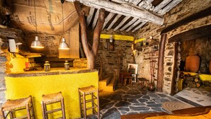 A rustic interior with a stone floor, wooden beams, a yellow bar area with stools, and a rustic ambiance. - Self catering El Mirador de Robledillo for 3 people (Robledillo de Gata)