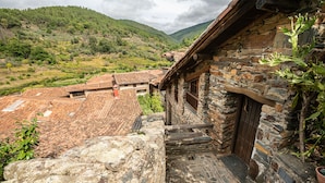 A stone building with a wooden staircase leading to a door, surrounded by a hilly landscape. - Self catering El Mirador de Robledillo for 3 people (Robledillo de Gata)