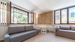 Una sala de estar moderna con un sofá gris, una mesita redonda y una silla blanca.