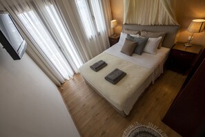 A neatly made bed with two folded towels, a bedside lamp, and a TV mounted on the wall. - VILLA KALLISTO,2BR,2BTH VILLA WITH PRIVATE POOL AND STUNNING SEA VIEWS (SKIATHOS)