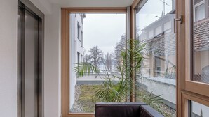 A balcony with a view of a residential area, a potted plant, and a leather sofa. - Exclusive new apartments with a romantic location at the small sailing port (Überlingen)