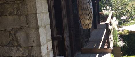 A rustic wooden building with a stone wall, a wooden door, and a hanging light fixture.