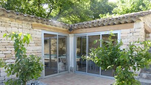 Ein Patio mit Steinmauern, gefliestem Boden und zwei Kübelpflanzen.