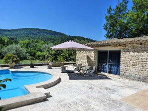 A swimming pool with a stone patio, outdoor furniture, and a stone building with a tiled roof. - Large self-contained studio with swimming pool in a nest of greenery in the heart of the Luberon (Saignon)