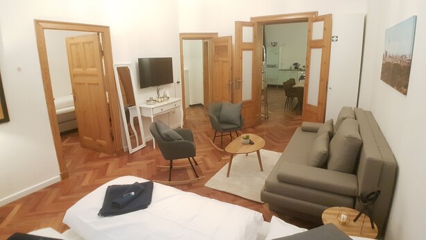 Ein kompakter Wohnbereich mit Bett, Sofa, Fernseher, Schreibtisch und Essecke.
