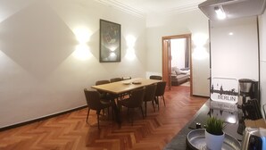 Ein Essbereich mit Holztisch und -stühlen, einem Gemälde an der Wand und einer Küchenzeile mit einem 'BERLIN'-Schild.