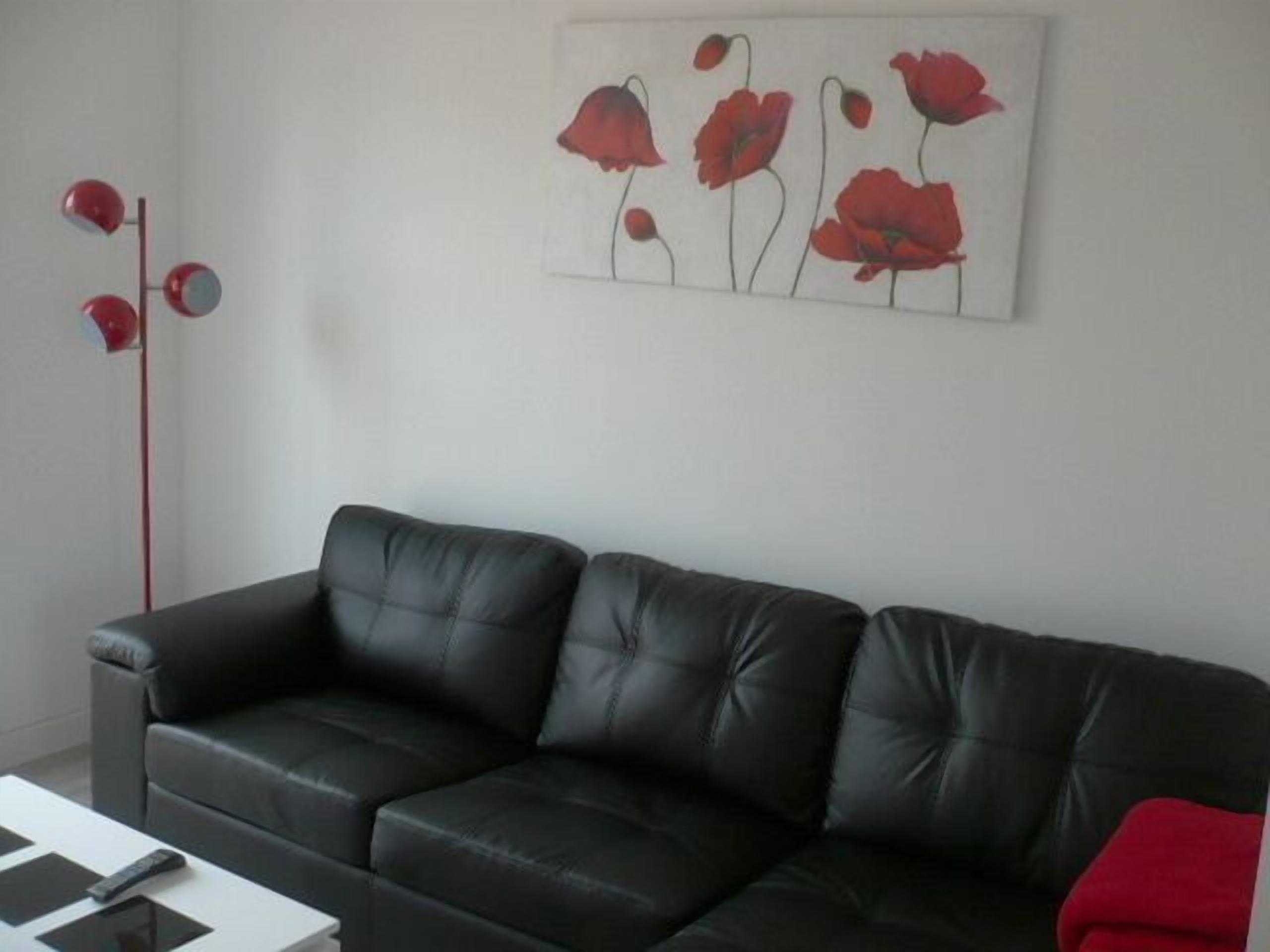 A black leather sofa in a room with a white wall.