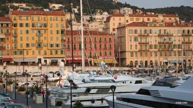 Un port de plaisance où sont amarrés de nombreux bateaux, entouré de bâtiments aux couleurs vives, dotés de balcons.