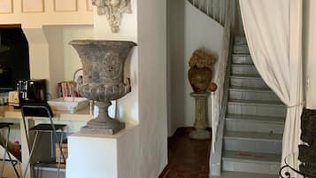 Un escalier orné d’une enseigne indiquant « MAISON », un grand vase et une sculpture fixée au mur.