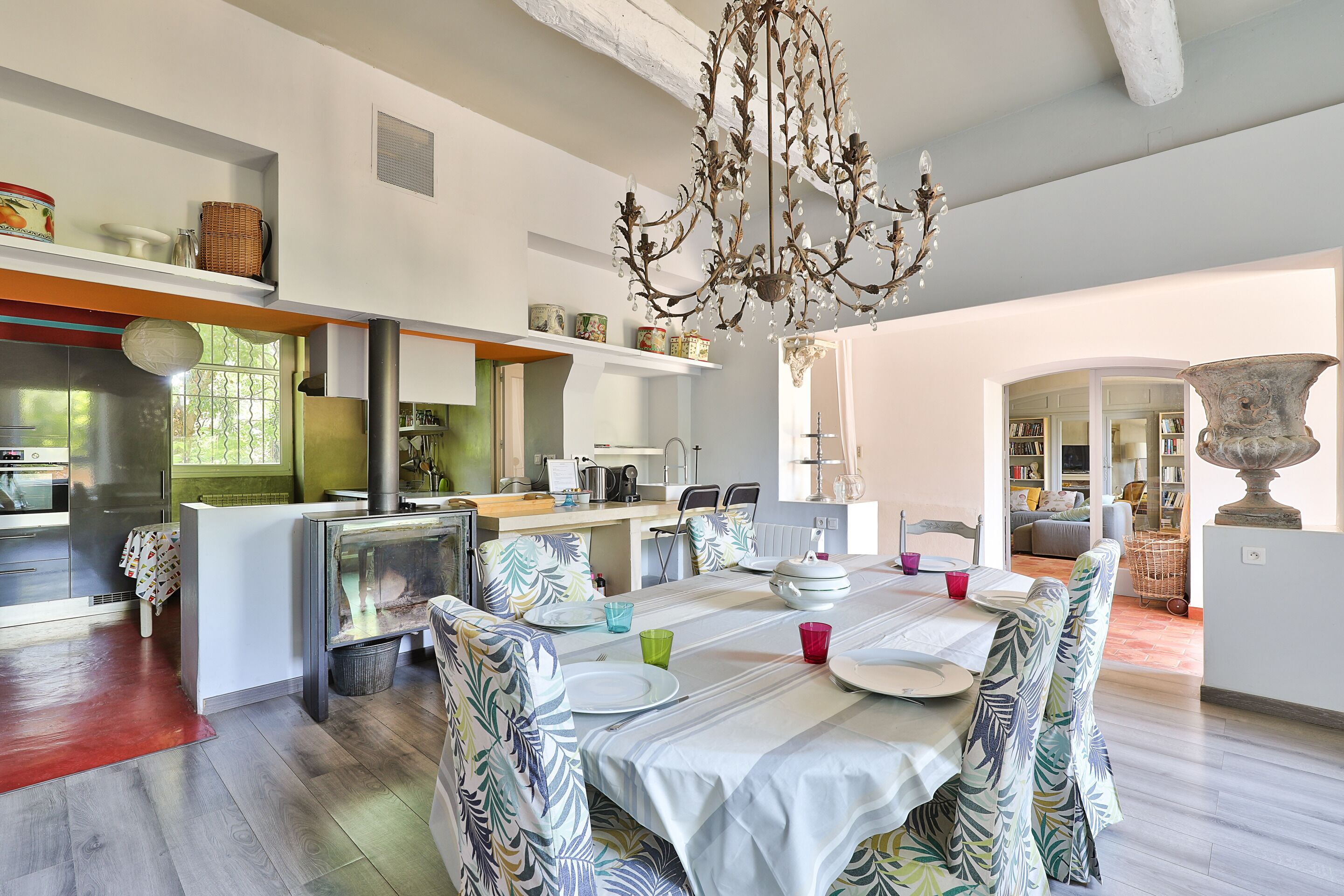 Un vaste espace dédié à la salle à manger, avec une grande table, des chaises à motifs et un lustre.