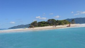 A beach with clear turquoise water, a sandy shore, and a few people.