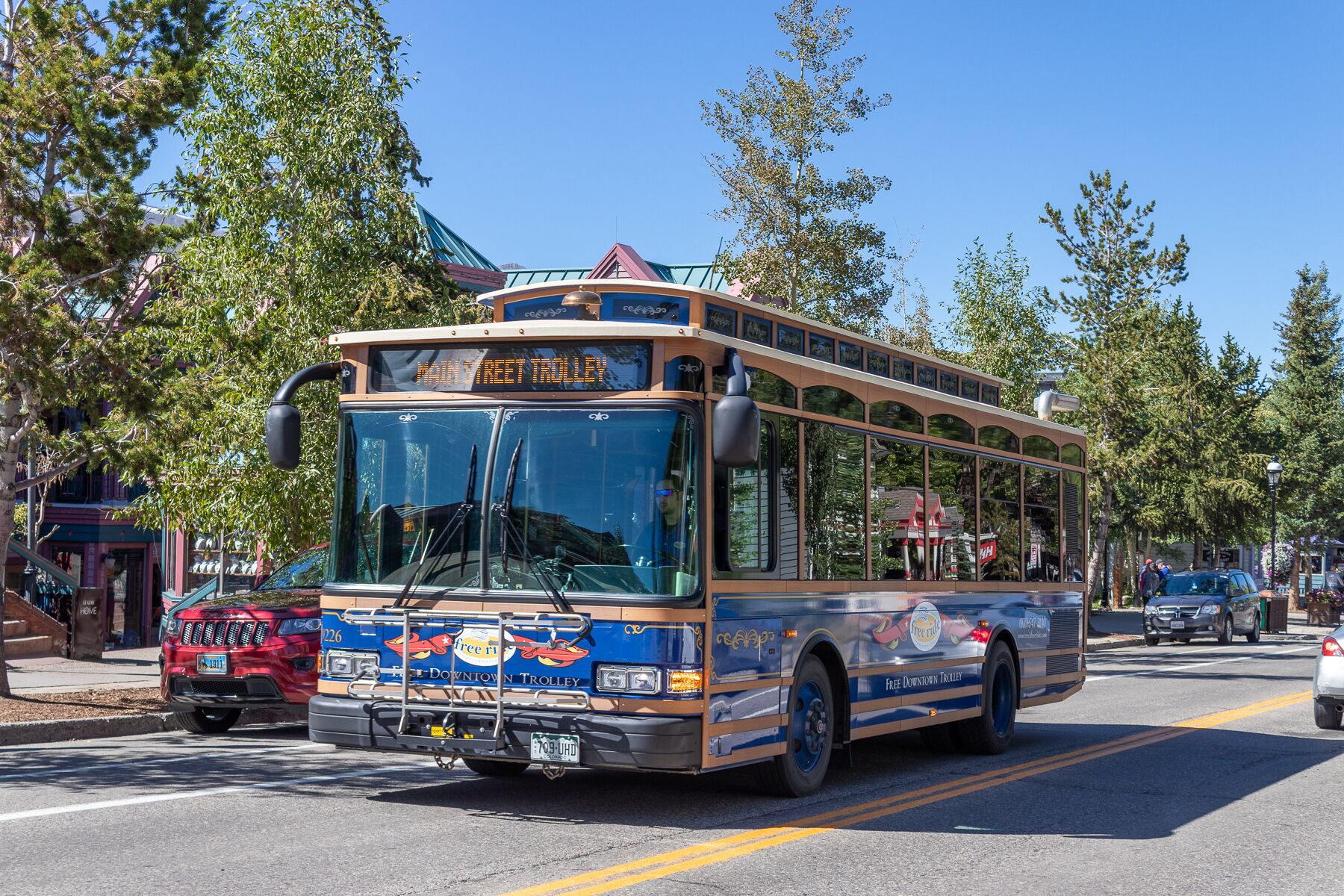 A trolley with 'Free Downtown Trolley' branding, parked on a street with trees and buildings.