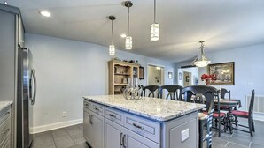 A kitchen with a central island, a dining area with chairs, and a refrigerator. - Cottage on the Boulevard - Renovated, Historic Downtown Wendell-3 Beds, 2 Baths (Wendell)