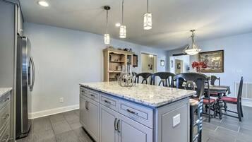 A kitchen with a central island, a dining area with chairs, and a refrigerator.