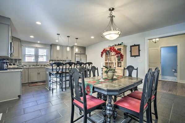 A spacious kitchen with modern appliances, a dining area with a large table and chairs, and a chandelier.