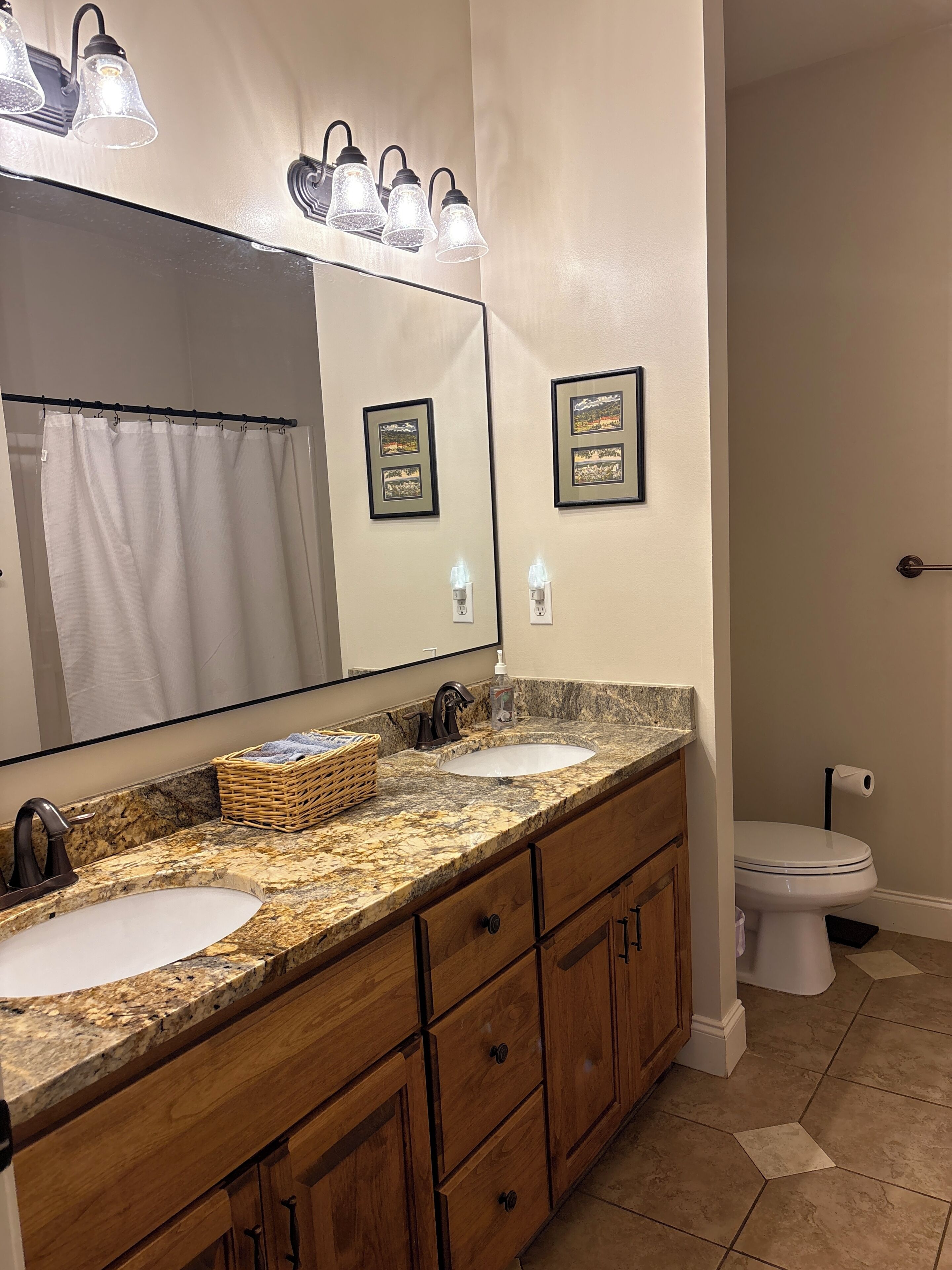 Ein Badezimmer mit einem Doppelwaschtisch, einem großen Spiegel und einer Toilette.