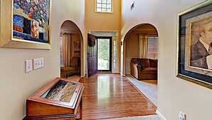 A hallway with wooden flooring, a door leading outside, and a couch in the background. - Your Home Away From Home (Lexington)