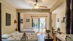A hotel room with two beds, a ceiling fan, a dining area, and a view of the outdoors. - Moonshine Hotel (Playa del Carmen)