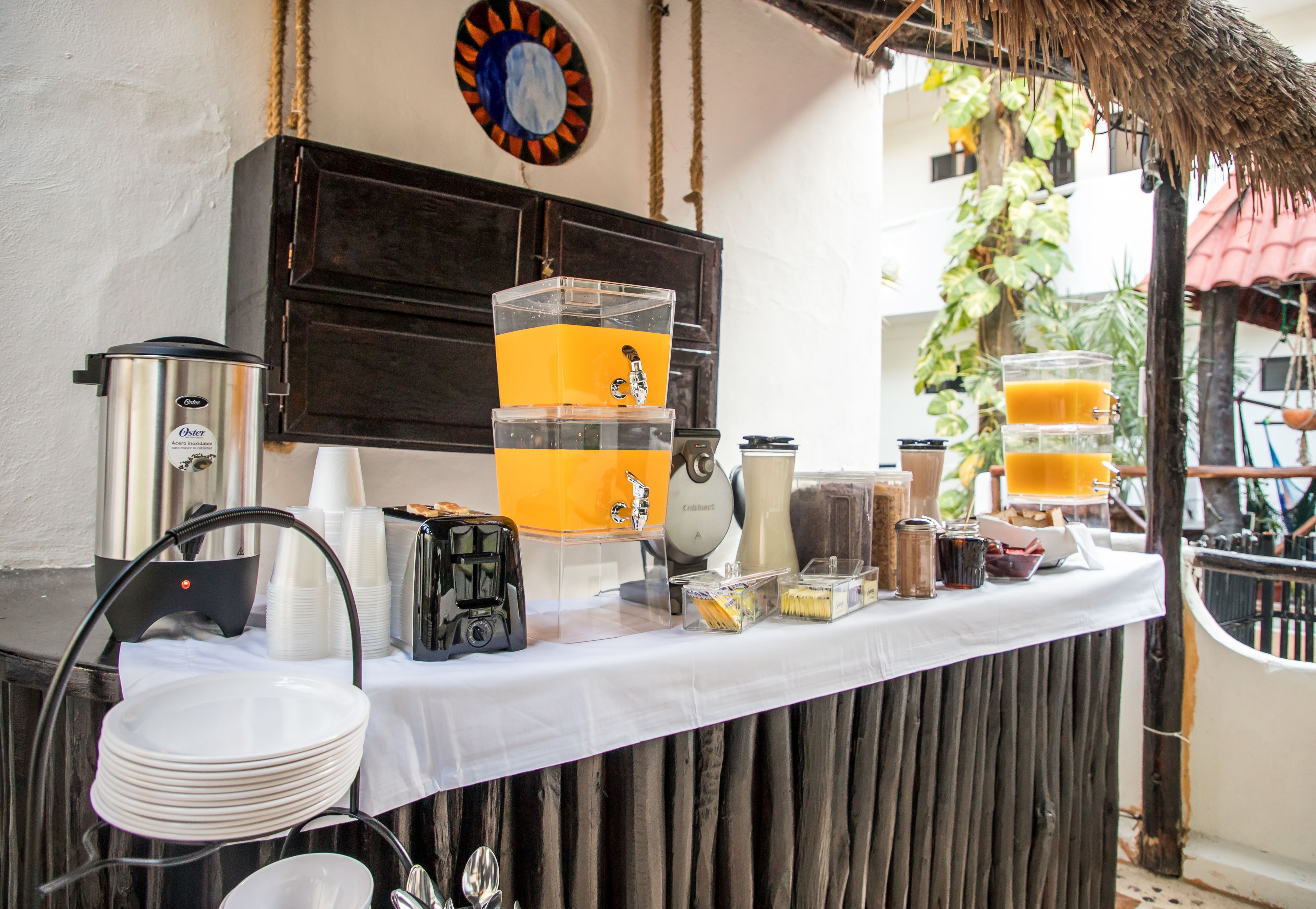 Un banco colazione con una macchina del caffè, succo d'arancia e diversi cibi.
