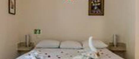 A bedroom with a bed, pillows, a framed picture, and a decorative item on the wall.