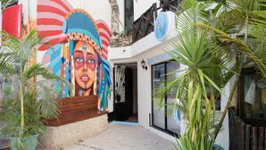 A building with a colorful mural, a reception area, and potted plants. - Moonshine Hotel (Playa del Carmen)