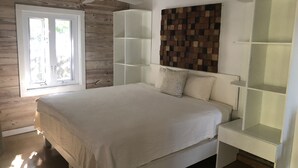 A bedroom with a bed, a ceiling fan, a window, and built-in shelving. - Peaceful Waterside Eco-Friendly Guest House on Stocking Island (Great Exuma)