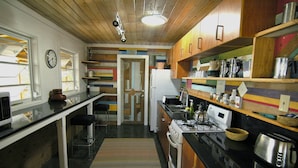 A kitchen with wooden cabinets, a stove, and various kitchen appliances. - Peaceful Waterside Eco-Friendly Guest House on Stocking Island (Great Exuma)