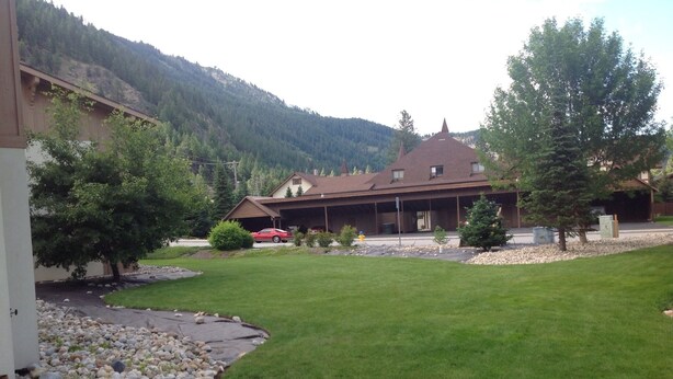 A residential area with a well-maintained lawn, a red car parked in the driveway, and a house with a brown roof and multiple windows. - Welcome to the Bean's Pod :-) (Leavenworth)