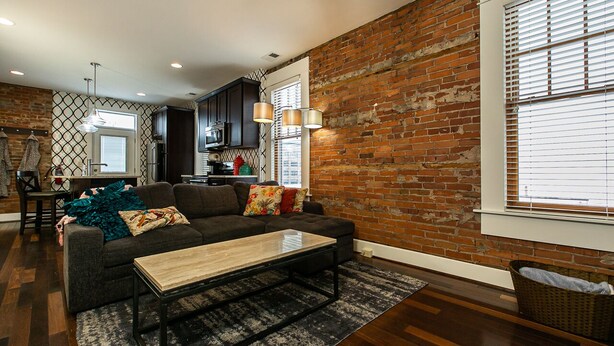 A living room with a dark sofa, a wooden coffee table, and a patterned rug. - Drake House: City View (Private Hot Tub) (Dubuque)