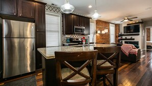 A modern kitchen with stainless steel appliances, dark wooden cabinets, and a central island with bar stools. - Drake House: City View (Private Hot Tub) (Dubuque)
