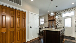 A kitchen with a central island, wooden cabinets, a brick backsplash, and pendant lighting. - Drake House: City View (Private Hot Tub) (Dubuque)