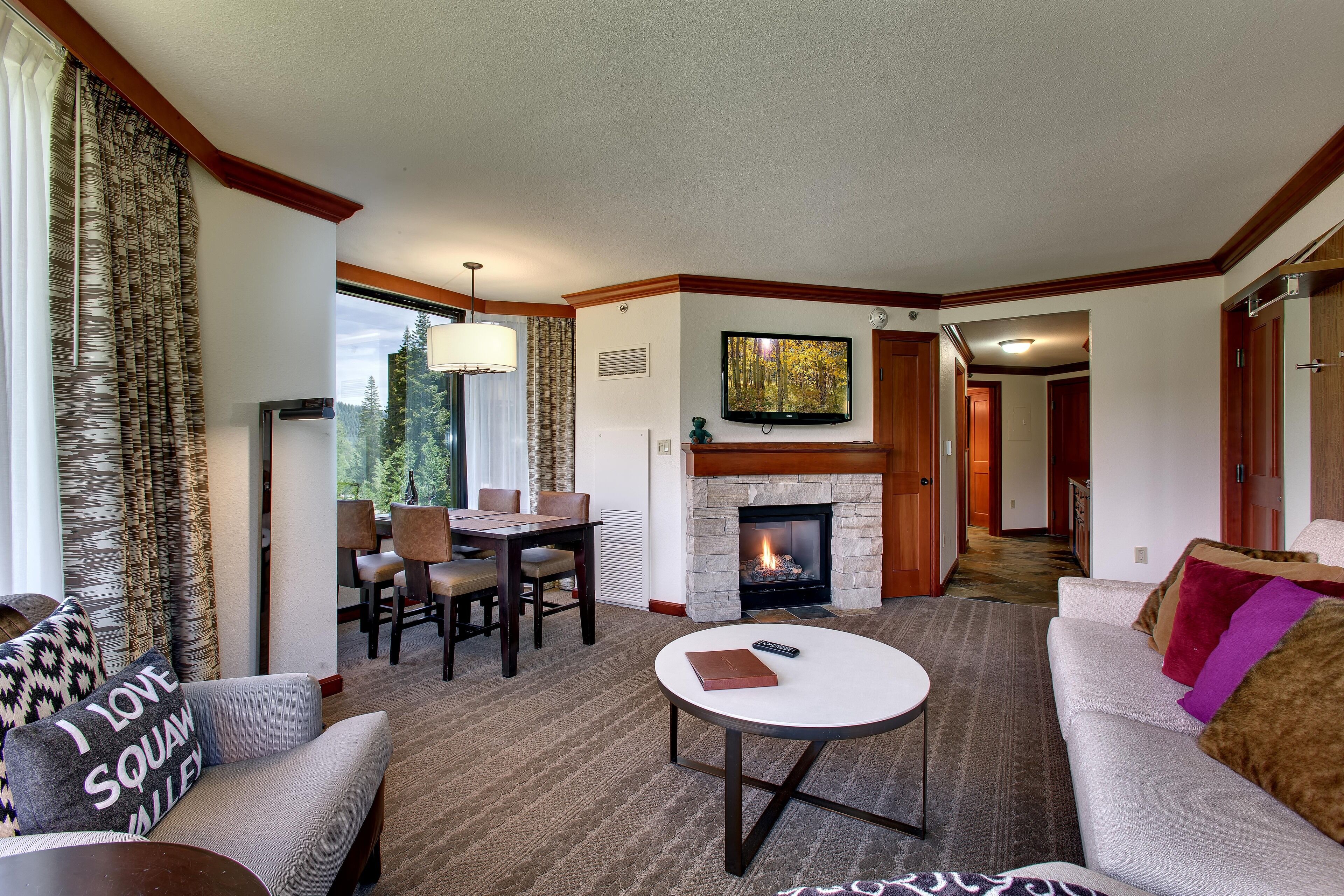 A living room with a fireplace, a dining area, and a sofa with a throw pillow.