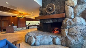 Un hall con chimenea de piedra, un mostrador de recepción y una zona de estar.