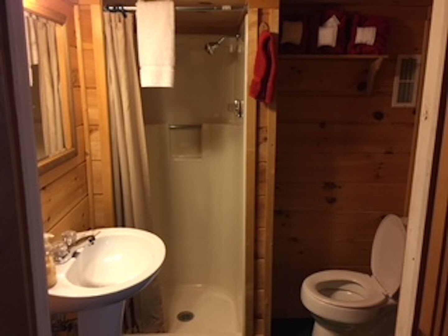 Un baño pequeño y funcional con ducha, inodoro y lavamanos.