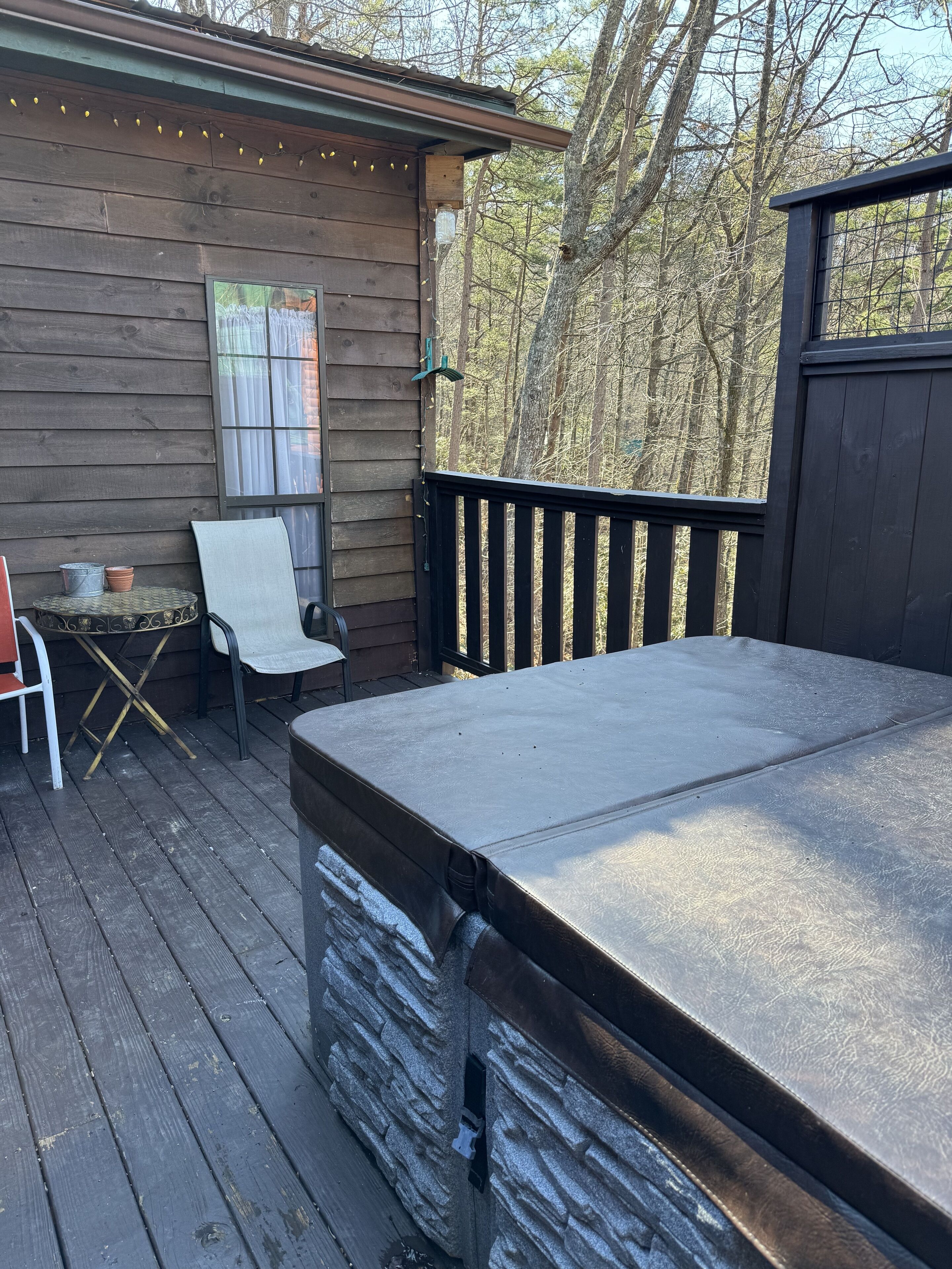 A wooden deck with a covered seating area, a table, and chairs.