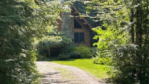A gravel path leading to a stone cabin surrounded by dense greenery. - Fabulous Log Cabin: the perfect getaway with new  pickleball court and pool! (Monterey)
