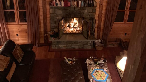 A cozy cabin interior with a stone fireplace, wooden walls, and a lofted ceiling. - Fabulous Log Cabin: the perfect getaway with new  pickleball court and pool! (Monterey)