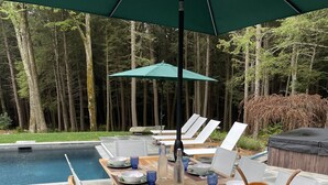 An outdoor dining area with a pool, surrounded by trees. - Fabulous Log Cabin: the perfect getaway with new  pickleball court and pool! (Monterey)