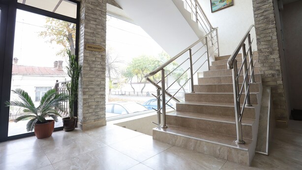 A hotel entrance with a staircase, potted plants, and a sign indicating the breakfast area. - Tourist INN Hotel (Tashkent)