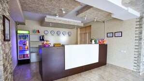 A reception area with a reception desk, a beverage dispenser, clocks on the wall, and a reception sign. - Tourist INN Hotel (Tashkent)