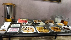 A buffet table with various food items and a coffee maker. - Tourist INN Hotel (Tashkent)