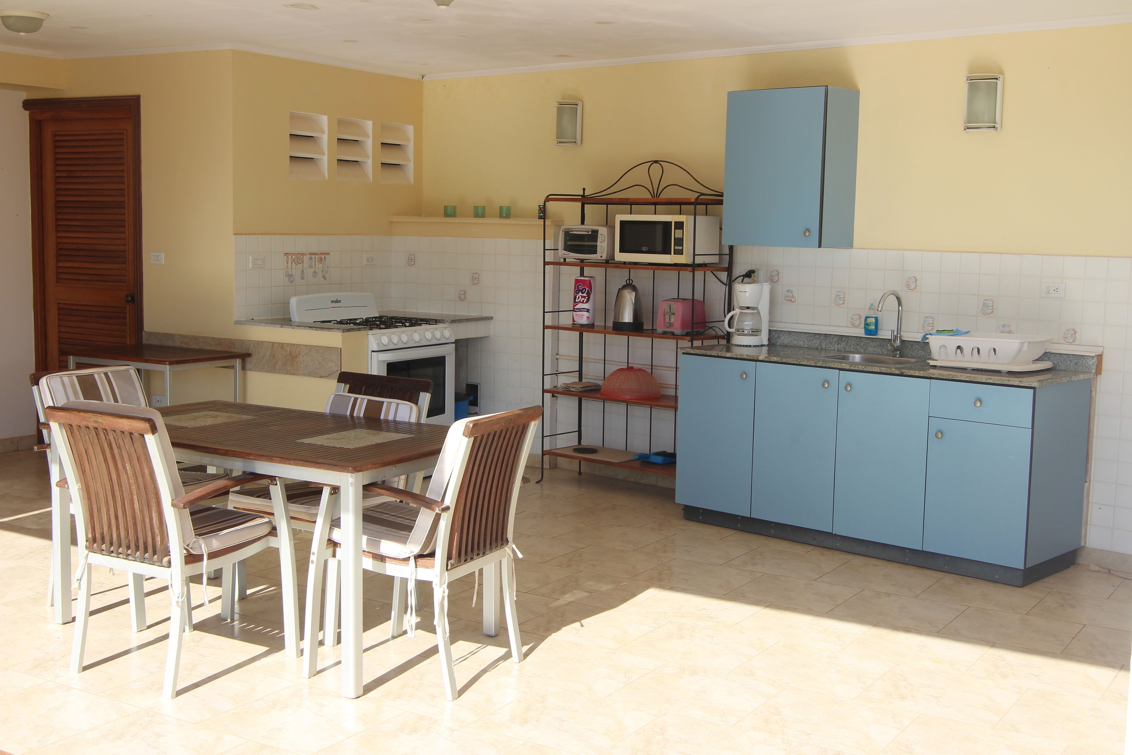 Una cocina con una mesa y sillas, estufa, microondas y armarios.