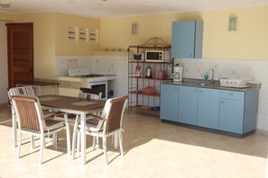A kitchen with a dining table and chairs, a stove, a microwave, and cabinets.