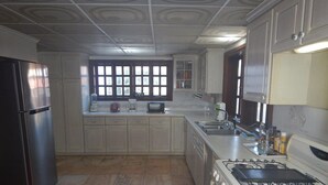 Una cocina con refrigerador, estufa, lavaplatos y ventana.