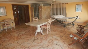 Una habitación amplia con una mesa de comedor, sillas, una hamaca y un ventilador de techo.